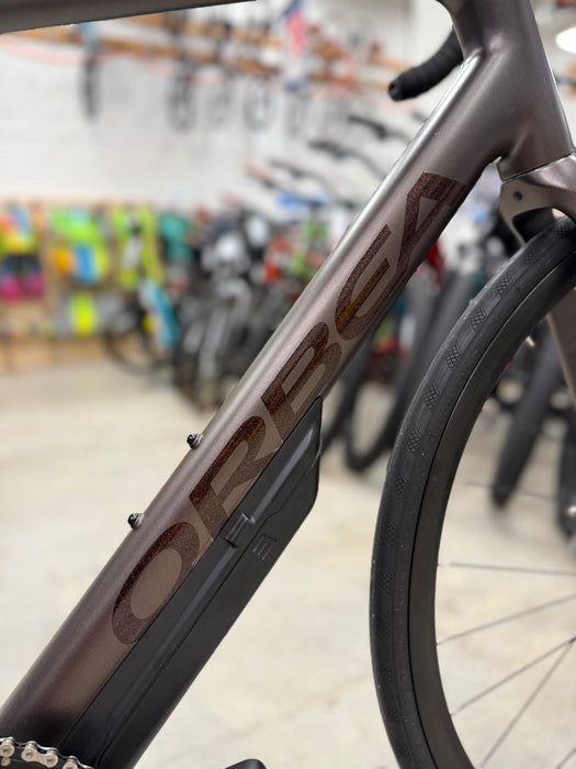 Close-up of a bicycle frame with 'Orbea' branding in a bike shop setting.